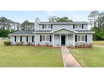 Charming two-story home with a cozy front porch and a well-maintained lawn and manicured shrubs at 100 Fairview Dr, Stockbridge, GA 30281