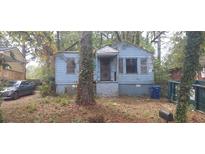 Exterior view of a blue home with bars on the windows, surrounded by trees at 1182 Bronx Nw St, Atlanta, GA 30314