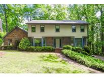 Charming two-story home with brick and siding, surrounded by mature trees and manicured landscaping at 4953 Mcpherson Ne Dr, Roswell, GA 30075