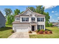 Charming two-story home with a white brick facade, attached garage, manicured lawn, and beautiful landscaping at 7455 Easton Valley Ln, Cumming, GA 30028