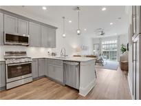 Open kitchen featuring stainless steel appliances, light gray cabinetry, and an island with quartz countertop at 1055 Piedmont Ne Ave # 409, Atlanta, GA 30309
