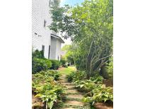 Stone pathway through lush backyard garden, leading to well-manicured lawn and landscaping at 6575 Eli Davis Rd, Cumming, GA 30040