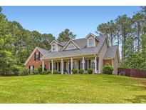 Charming home featuring a brick and siding exterior, complemented by a well-manicured lawn and mature trees at 125 Murphy Creek Ln, Fayetteville, GA 30215