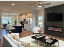 Open living room with modern fireplace, ceiling fan, hardwood floors and kitchen in the background at 1923 Cassia Aly, Kennesaw, GA 30144