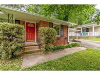 Charming brick home with a bright red front door and mature landscaping at 1145 Arbordale Dr, Decatur, GA 30033
