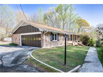 Charming brick home featuring an attached garage, inviting curb appeal, and lush landscaping at 5925 Old Bill Cook Rd, South Fulton, GA 30349