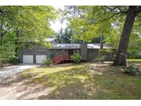 Charming gray home with a two-car garage, inviting red front deck and mature trees at 633 Iris Rd, Pine Lake, GA 30072