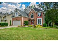 Charming brick home featuring a well-manicured lawn, attached two-car garage, and beautiful landscaping at 2002 Fairbrook Ln, Woodstock, GA 30189