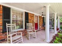 Charming covered front porch featuring rocking chairs, red door, and stately columns at 2381 Woodacres Rd, Atlanta, GA 30345
