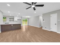 Bright living room with wood floors and white kitchen with breakfast bar in an open floorplan at 1829 Herringbone Holw, Lithonia, GA 30058
