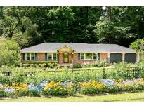 Charming brick ranch-style home featuring a lush front yard with vibrant flowers and mature trees at 1652 Oak Grove Rd, Decatur, GA 30033