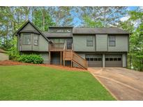Split-level home with an olive exterior, deck, two-car garage, and green lawn at 4788 Rock Island Nw Ln, Acworth, GA 30102