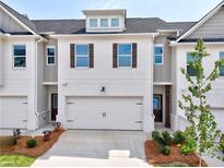 Charming townhome featuring a two-car garage, neat landscaping, and a modern white brick facade at 1277 Fern Ridge Ct # 22, Norcross, GA 30093