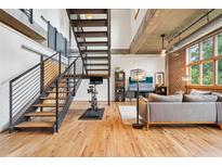 Stylish living room featuring hardwood floors, brick accent wall, staircase, and modern decor at 640 Glen Iris Ne Dr # 609, Atlanta, GA 30308