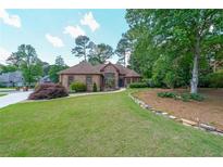 Beautiful brick home with a manicured lawn and mature trees, creating a welcoming curb appeal at 6510 Newcastle Way, Cumming, GA 30040