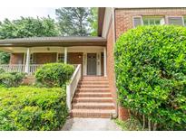Charming brick home featuring a welcoming front porch with brick stairs and lush landscaping at 7310 Ne Wynhill Ne Dr, Atlanta, GA 30328