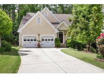 Inviting beige home featuring a two-car garage, manicured lawn, and mature trees at 230 Ridge Point Ct, Alpharetta, GA 30022
