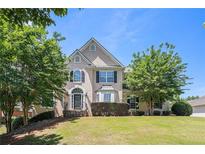 Two-story home with a manicured lawn and mature trees, creating a welcoming curb appeal at 1035 Eagles Brooke Dr, Locust Grove, GA 30248