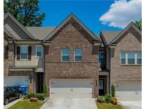Charming brick townhome featuring a two-car garage and well-maintained landscaping at 221 Irwell Path, Lawrenceville, GA 30044