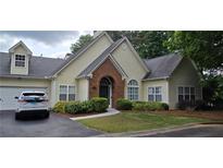 Charming home with brick entryway, attached garage, manicured lawn and lush landscaping at 1231 Creek Forest Ln, Austell, GA 30106