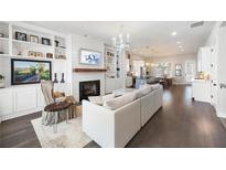 Bright living room with fireplace, built-in shelves, hardwood floors, and open layout to kitchen and dining area at 217 Napa Dr, Woodstock, GA 30188