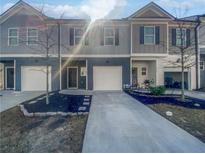 Modern townhome featuring a gray exterior with a private garage and manicured landscaping at 7119 Gladstone Cir, Lithonia, GA 30038