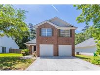 Charming two-story brick home featuring a two-car garage, well-manicured lawn and verdant trees at 4915 Truitt Ln, Decatur, GA 30035