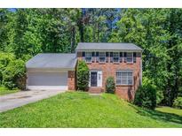 Charming two-story brick home featuring a well-maintained lawn, attached garage, and mature trees at 1076 Plantation Se Blvd, Conyers, GA 30094