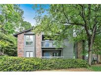 Charming condo exterior with a brick facade and second-story balcony surrounded by mature trees and landscaping at 205 Tuxworth Cir # 205, Decatur, GA 30033