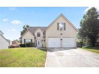Charming two-story home featuring a two-car garage and a well-maintained front lawn on a clear, sunny day at 7270 Williamsburg Dr, Riverdale, GA 30274
