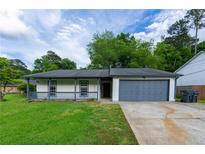 Charming single-story home with a well-maintained lawn, a cozy porch, and attached garage at 1451 Brays Mill Trce, Lawrenceville, GA 30044