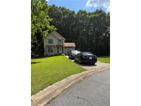 Charming two-story home with a lush green lawn and private driveway, nestled among mature trees at 9526 Autumn Ct, Jonesboro, GA 30238