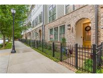 Charming townhomes with brick facade, arched entryways, and black wrought iron fences along a tree-lined street at 976 Memorial Se Walk, Atlanta, GA 30316