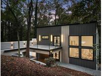 Modern home exterior featuring a cantilevered balcony, standing seam metal, and woodland setting at 1153 Dawn View Nw Ln, Atlanta, GA 30327