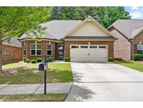 Charming brick home with a two-car garage, a well-manicured lawn and mature landscaping at 2212 Nichols Valley Drive, Dacula, GA 30019