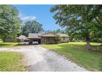 Charming single-story home featuring a gravel driveway and mature trees and covered parking at 578 Laney Rd, Locust Grove, GA 30248