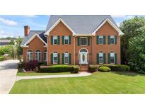 Charming brick home featuring a manicured lawn, green shutters, and a welcoming front entrance at 1402 Bromley Dr, Snellville, GA 30078