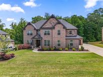 Two-story brick home showcasing a well-manicured lawn and beautiful landscaping at 317 Basel Way, Hampton, GA 30228