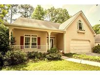 Charming, single-story home with light yellow siding, complemented by a cozy front porch and an attached garage at 4481 Mccart Cv, Stone Mountain, GA 30083