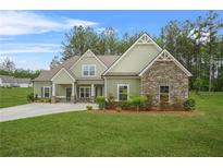 Charming single-story home featuring a mix of stone and green siding, complemented by a lush green lawn at 100 Nemoura Ct, Fairburn, GA 30213