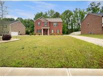 Charming two-story brick home with a lush green lawn and beautiful landscaping in a quiet, residential neighborhood at 1477 Harlequin Way, Stockbridge, GA 30281