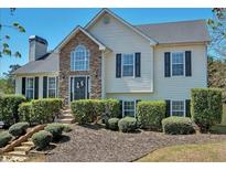 Charming two-story home featuring a stone facade, manicured landscaping, and a welcoming front entrance at 7020 Walnut Mill Lndg, Cumming, GA 30040