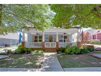 Charming blue house featuring a welcoming front porch with white railings, a green lawn, and mature trees at 230 Ryan Ln, Covington, GA 30014