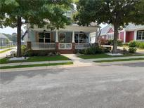 Charming blue home featuring a welcoming front porch with white railings and beautifully landscaped yard with mature trees at 230 Ryan Ln, Covington, GA 30014
