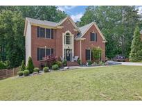 Charming two-story brick home featuring a well-manicured lawn and lush landscaping at 4410 Red Rock Pt, Suwanee, GA 30024