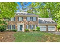 Charming brick two-story home with blue shutters and a well-manicured lawn, surrounded by mature trees at 4181 Singing Post Ne Ln, Roswell, GA 30075