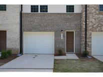 Charming townhome exterior features a one-car garage, a brown door, and well-maintained landscaping at 4970 Villager Ln, Stone Mountain, GA 30083