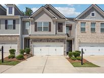 Charming townhome featuring a two-car garage and professionally landscaped front yard at 5527 Fairhaven Pl, Fairburn, GA 30213