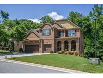 Charming two-story brick home featuring a three-car garage and a well-manicured front lawn at 1185 Gallatin Way, Suwanee, GA 30024