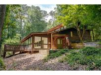 Inviting log home with a deck and lush landscaping creates a private and serene setting at 605 Ga 120 Hwy, Roswell, GA 30075